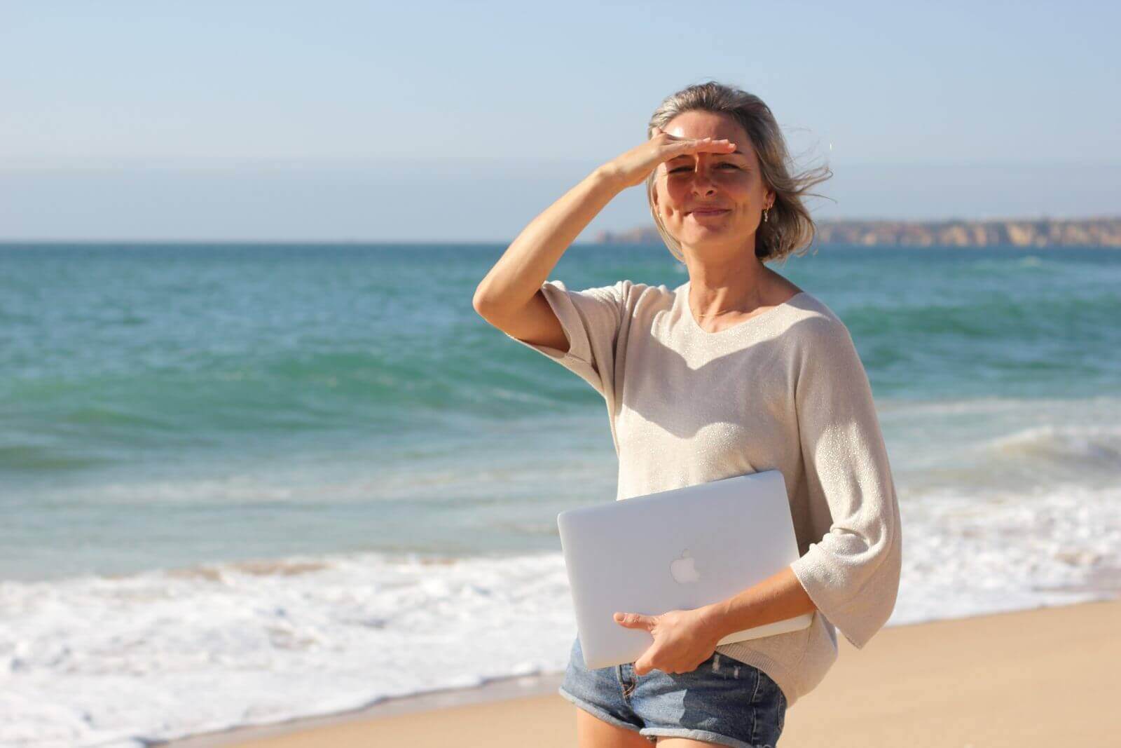 Sabine André, freelance SEO, sur la plage de Meia Praia avec son ordinateur